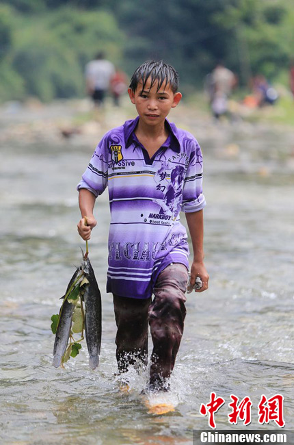 圖為7月9日，一名男孩在鬧魚節(jié)活動中抓到了兩條魚。譚凱興 攝