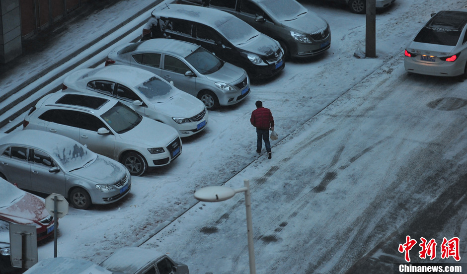 11月18日，行人在沈陽街頭的積雪中穿行。