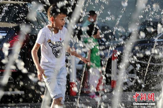 山西太原最高溫36℃,兒童在噴泉周圍戲水消暑。