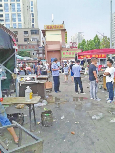 昨天，執(zhí)法人員在京廣路長江路口整治“僵尸圍擋”及圍擋內(nèi)的攤販。