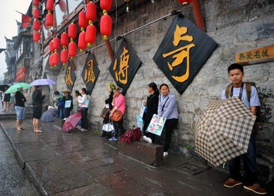 　4月29日上午11時20分，一些游客和古城當(dāng)?shù)氐木用穸阍谝粋€酒吧的屋檐下避雨。這些當(dāng)?shù)鼐用褚詾橛慰团恼罩\生，一場降雨讓他們的生意更加清淡。