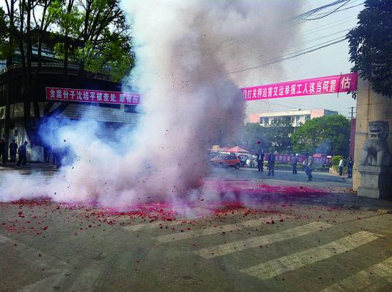 市民在普洱市主干道振興大道的金孔雀交通運(yùn)輸集團(tuán)有限公司門前燃放鞭炮，公司門前掛著“貪腐份子沈培平被查處，罪有應(yīng)得，大快人心。”的條幅