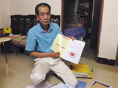 翻出一家網站贈予的“中國好人”證書，區(qū)少坤單膝跪在地上，“你看，我是中國好人啊。” 范春旭 攝