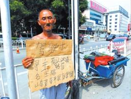 老人舉著牌子在路邊等候失主。京華時報記者譚青攝