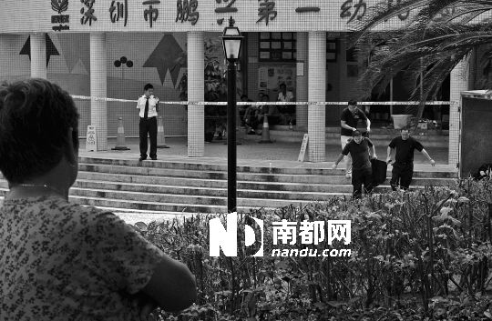 →7月19日，鵬興花園第一幼兒園門前，民警在現(xiàn)場進(jìn)行完勘查取證后，園長和保安的尸體被運(yùn)走。南都記者 徐文閣 攝