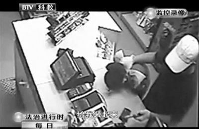 戴帽男子一手掐住加油站營業(yè)員，一手持發(fā)令槍指向另一營業(yè)員，要求“把錢給我裝起來”。
