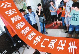 面對警方收繳的條幅，老板楊某也不好意思地用手遮擋臉
