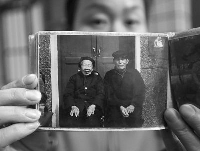 圖為孫女拿出兩位老人上世紀(jì)80年代在家門口的合影給記者看。記者楊濤 攝