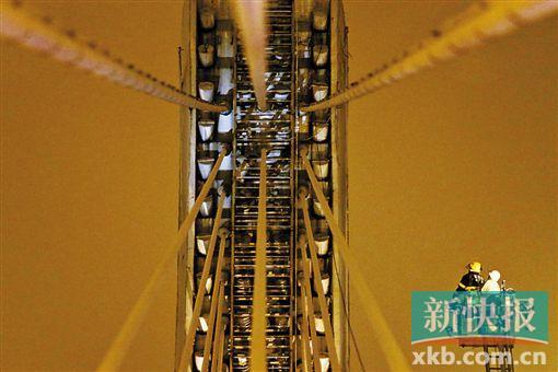 截至今日零時(shí)，男子仍未有下橋舉動(dòng)。圖為公安和消防人員乘消防云梯在高空上和男子交談。