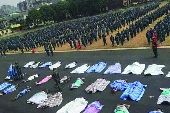 20多名女生躺在瀝青跑道上，身上嚴(yán)嚴(yán)實(shí)實(shí)地裹著棉被，接受太陽(yáng)的照曬。
