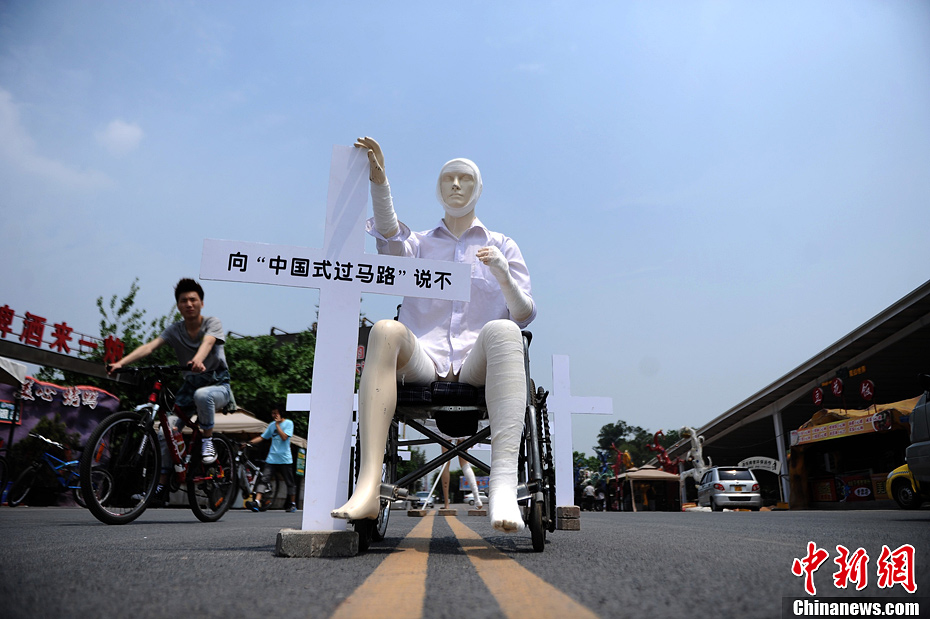4月16日，重慶市洋人街上擺放著兩個受了傷的塑料人像“模特”，旁邊十字架上寫著向“中國式過馬路”說不