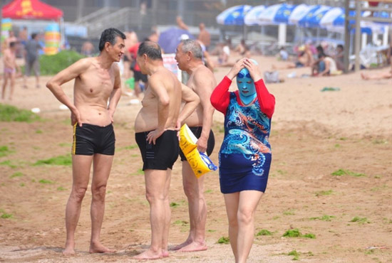 2013年7月3日，山東青島青島高溫來襲，“青島大媽”不懼滸苔，戴著“強(qiáng)盜面具”出現(xiàn)在海水浴場消暑降