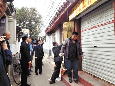 執(zhí)法人員拆除胡同里一家店面未經(jīng)審批的招牌。