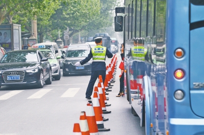 省人民醫(yī)院南門的路中間擺放反光錐，交警示意由西向東車輛從前方繞行。