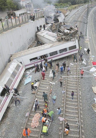 24日，救援人員在西班牙列車脫軌現(xiàn)場(chǎng)。一節(jié)車廂被強(qiáng)大的慣性拋上鐵道邊的高臺(tái)。