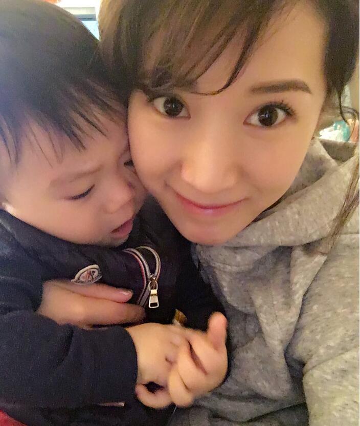 照片中李念狂吻兒子，小寶貝自顧自地玩著。
