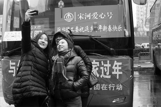 昨天上午8時，鄭州正道中環(huán)百貨廣場，準(zhǔn)備回家的老鄉(xiāng)在愛心大巴車前合影留念