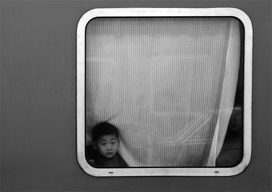 一個孩子把頭伸向窗外，他想再看送別的親人一眼