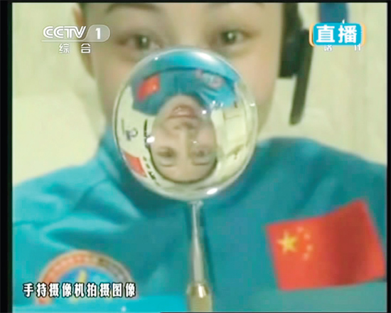 王亞平的倒影出現(xiàn)在水球中。新華社發(fā)（視頻截圖）