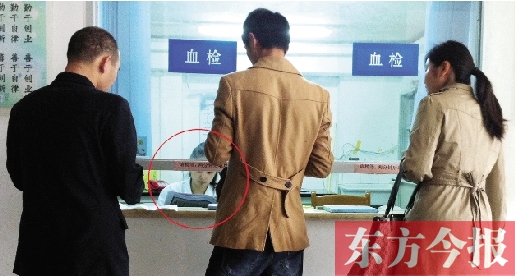 昨日，鄭州市二七區(qū)疾控中心辦證大廳，血檢窗口內(nèi)一名女工作人員，邊接受辦證者咨詢邊看報紙
