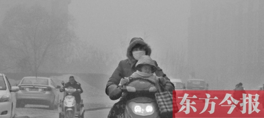 12月8日，鄭州市未來路上，一位市民帶著孩子在霧中騎行