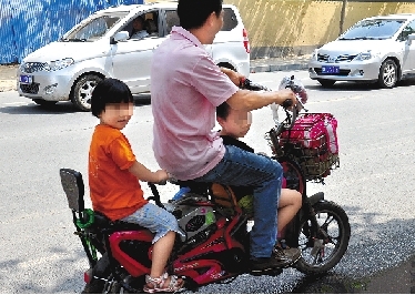 周先生騎著一輛低矮的電動(dòng)車帶著一對(duì)兒女，很不安全。