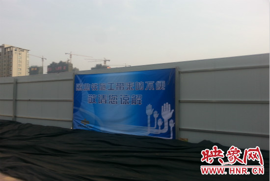 道路南側(cè)圍起了白色的圍擋，墻上標(biāo)示著“因地鐵施工帶來(lái)的不便敬請(qǐng)您諒解”的提示牌。