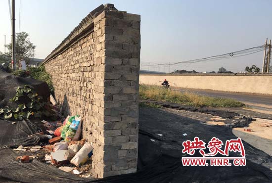 一墻之隔，一邊是道路，一邊是垃圾和荒草，市民質(zhì)疑其為遮羞墻。
