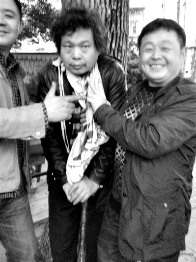兩名接訪人員與患有癌癥的訪民段新德合影時(shí)，面帶笑容擺出勝利的手勢。
