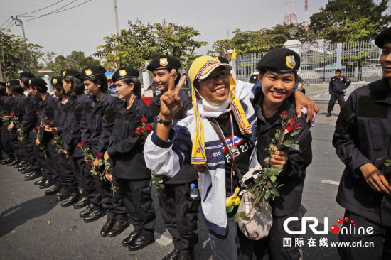 2013年12月03日,曼谷總理府與曼谷警署允許反政府示威民眾進(jìn)入,雙方進(jìn)入暫時(shí)“停戰(zhàn)”狀態(tài)迎接泰王生日。曼谷警察總署,女警們手持鮮花送給反政府示威民眾。圖片來源:Manish Swarup/東方IC