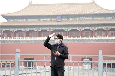 11月1日，北京大部分地區(qū)重度污染，一名游客戴著口罩在午門前揮手跟朋友打招呼。 實習(xí)生 王飛 攝