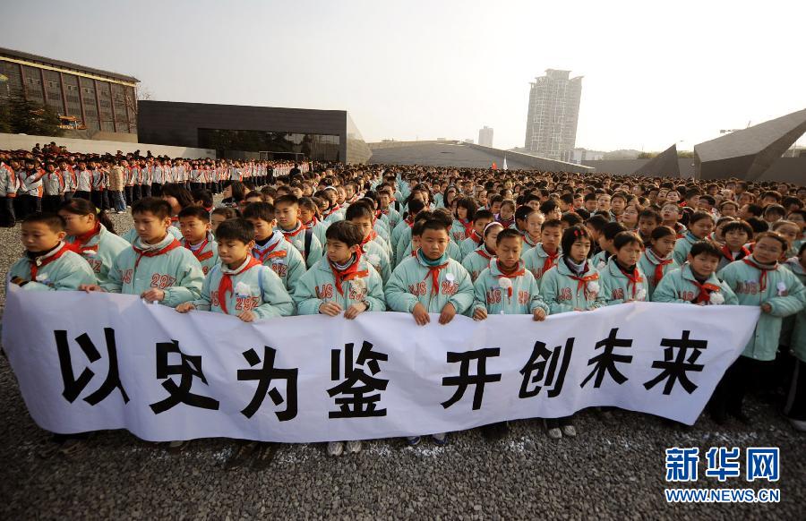 ，南京市小學生代表手持“以史為鑒 開創(chuàng)未來”的橫幅在南京大屠殺遇難同胞紀念館集會廣場參加悼念儀式?！? width=