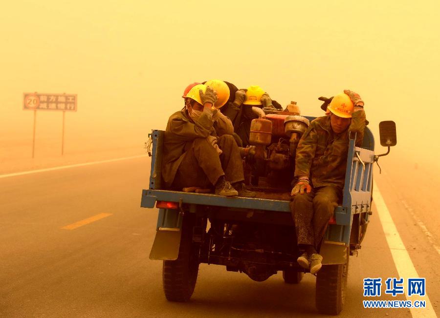 4月23日，一輛拉載公路施工人員的三輪車(chē)在沙塵暴中行駛在酒泉市瓜州縣城郊的公路上。