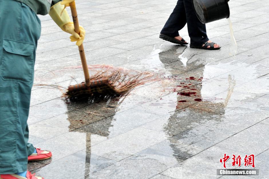 圖為環(huán)衛(wèi)工人在清理案發(fā)地點(diǎn)的血跡。