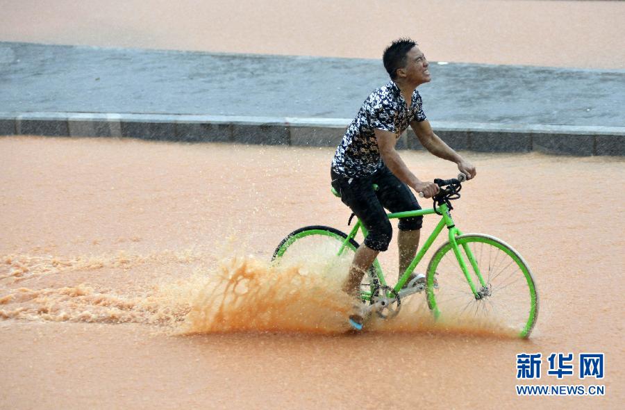 5月11日，一名行人在深圳街頭冒雨騎行。
