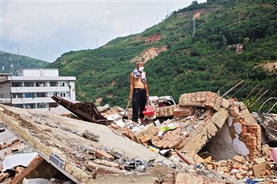 8月9日,龍頭山鎮(zhèn),一位老者在自家房屋廢墟上尋找家當(dāng)。