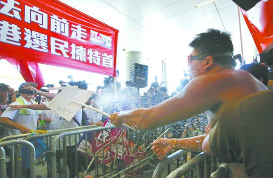 17日，在香港立法會(huì)外，一名反對(duì)政改的男子向支持派人群投擲標(biāo)牌。
