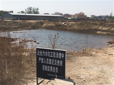 化肥廠滲坑的三分之一經(jīng)過(guò)治理，但水質(zhì)仍然呈黃褐色。