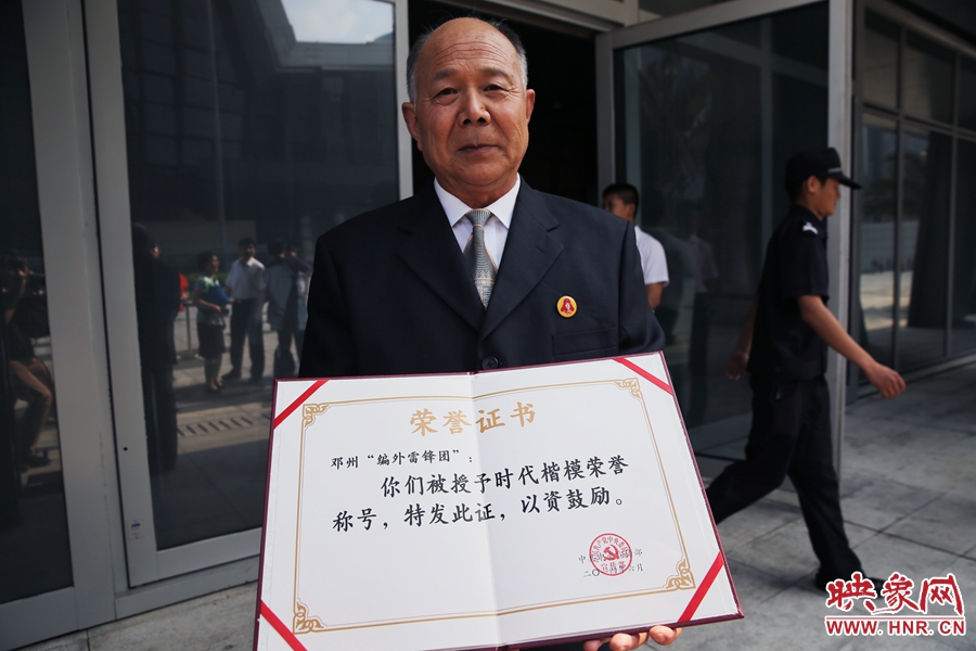 河南鄧州“編外雷鋒團”團長宋清梅向眾多記者展示中宣部授予的“時代楷?！睒s譽證書。