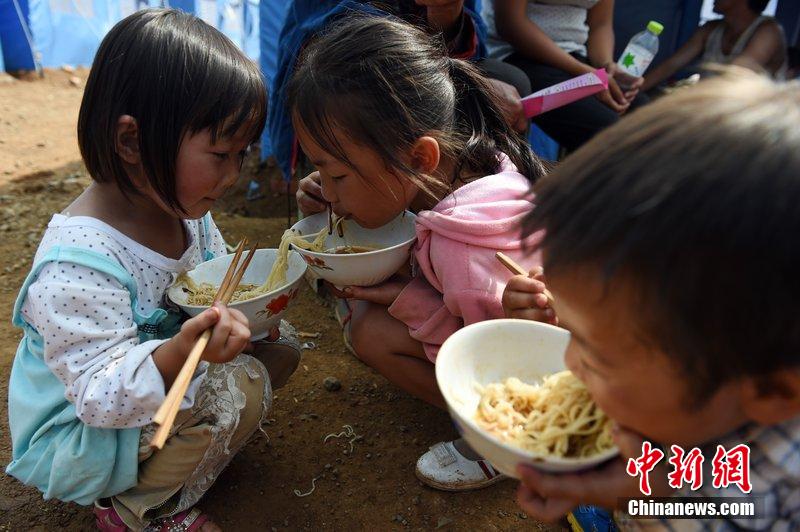 2014年8月6日，云南魯?shù)辇堫^山災(zāi)區(qū)，兒童在帳篷外吃飯。