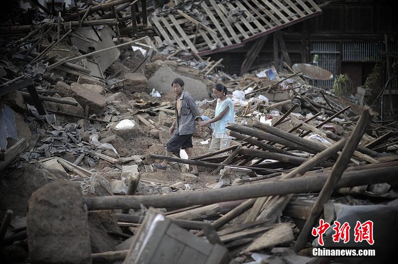 2014年8月5日，云南昭通龍頭山鎮(zhèn)老街，一對夫妻從居住房屋的廢墟中走過。