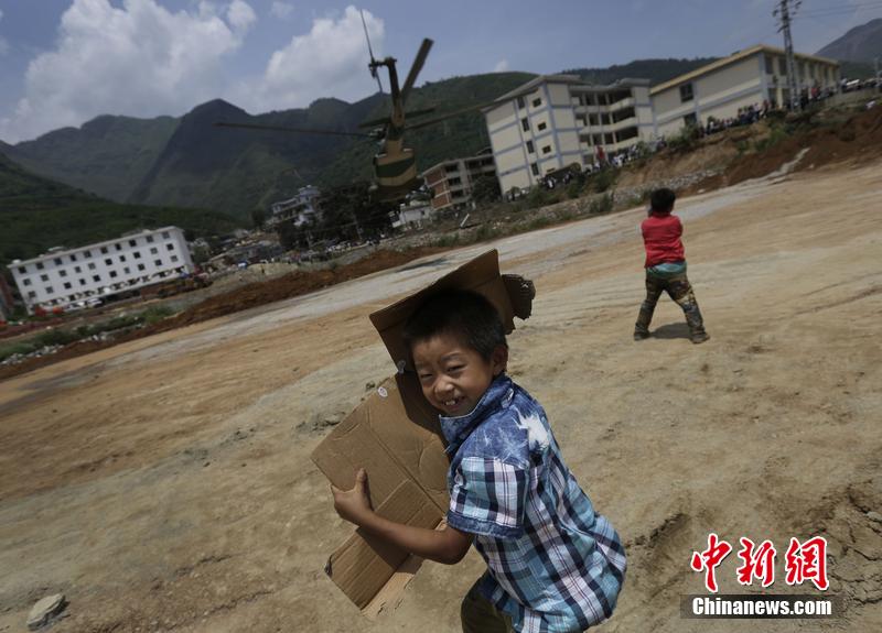云南省昭通市魯?shù)榭h發(fā)生6.5級地震。幾個孩子在直升機降落的平地上玩耍。