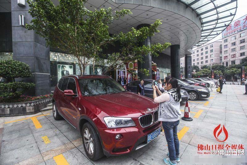 一輛停在停車位上的寶馬轎車，被墜落的樹枝砸中，樹枝徑直插入車內(nèi)，現(xiàn)場(chǎng)引發(fā)不少市民圍觀拍照。