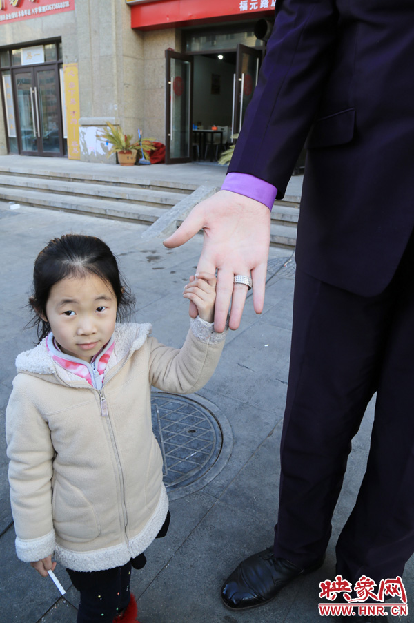 巨人“張歡”牽著一名漂亮的小女孩，兩人的手大小對(duì)比非常明顯。