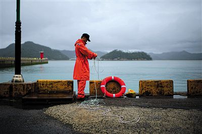 7月6日，韓國珍島，一名海岸警察在港口系救生圈。4月，客輪在珍島近海發(fā)生沉船事故后，仍有11人下落不明。