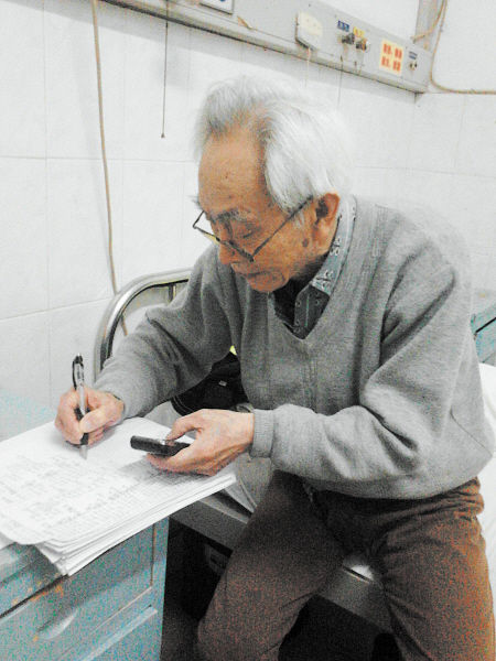 杜修源老人埋頭寫著特殊的“日記”。 李卓 攝