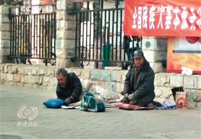 工人體育場北路，兩位乞討者路邊乞討，并輪流扮成“病人”（躺地者）。 央視截圖