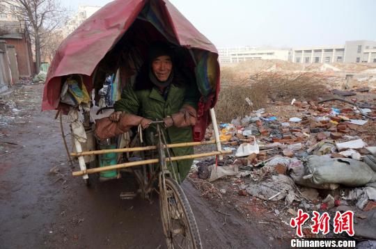 圖為老人走出窩棚，推著三輪車準備出去撿拾廢品。周小云 攝